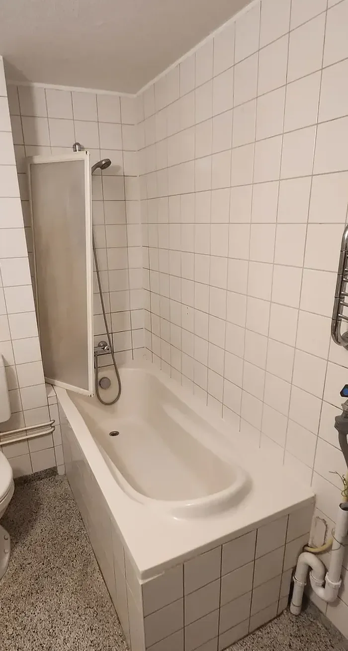 Oude badkamer met ligbad met badscherm en witte tegels