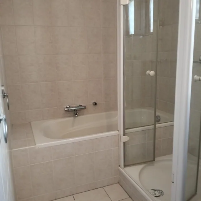 Oude badkamer met ligbad, douchecabine met kwartronde bak en beige tegels